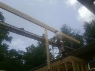 Carpenter setting a ridge beam over a new addition frame — Ice Dam Removal by Roofing Brothers in Jay Em