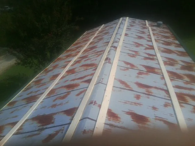 Rusted metal roof panels with new wood purlins before replacement — Storm Damage Roof Repair in Jay Em by Roofing Brothers