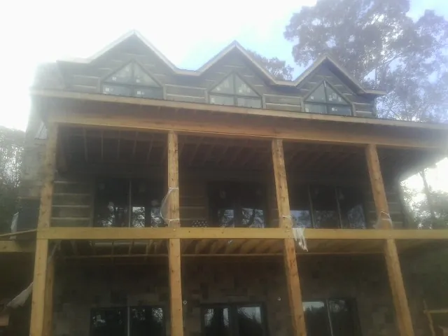Dormers and porch framing on a large log home under construction — Roof Coating work by our crew in Jay Em