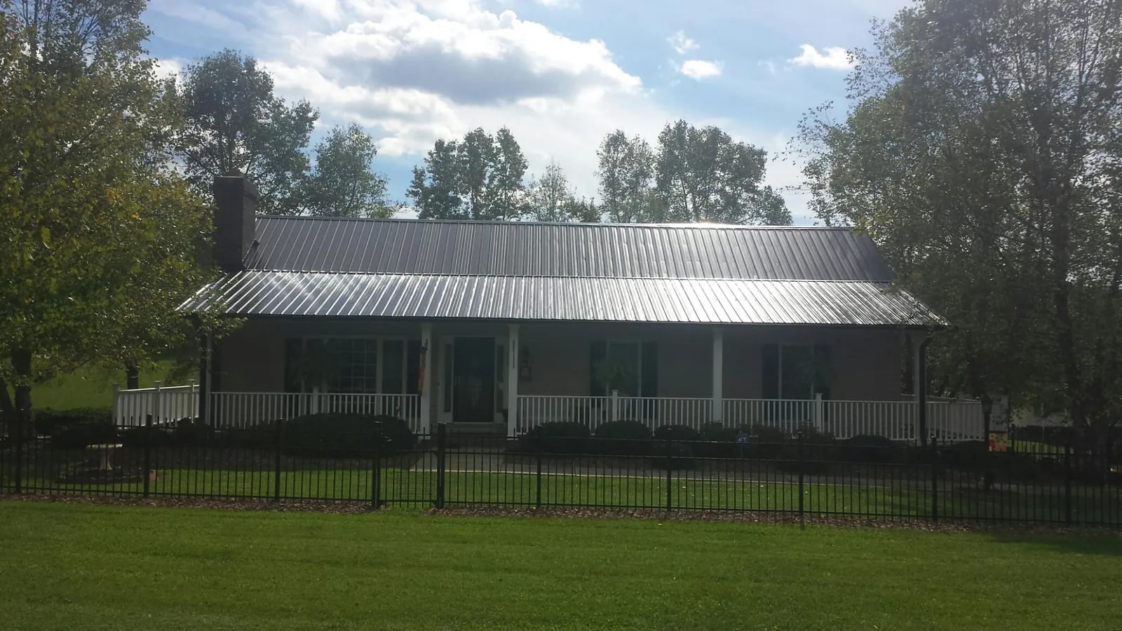 Gray metal roof on a brick ranch with a full width front porch — Gutter Guard Installation work by our crew in Jay Em