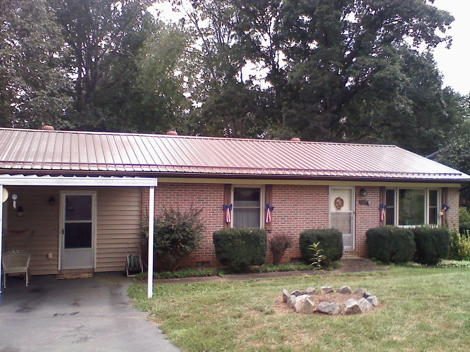 Bronze metal roof and carport on a brick ranch home — Roof Repair work by our crew in Jay Em